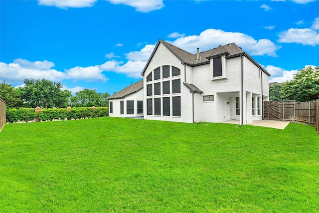 rear view of house with a patio area, a lawn, and fence