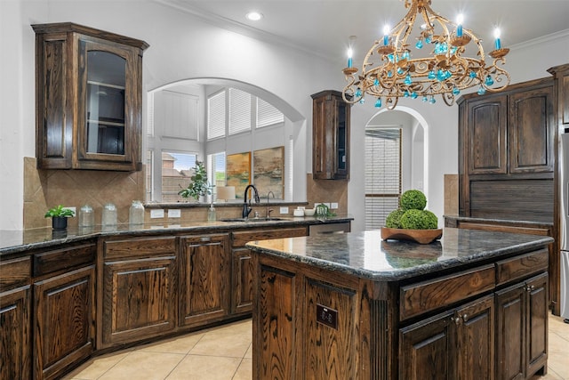 kitchen featuring light tile patterned floors, glass insert cabinets, crown molding, and a sink