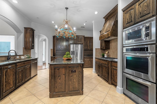 kitchen featuring a sink, a kitchen island, arched walkways, appliances with stainless steel finishes, and light tile patterned flooring