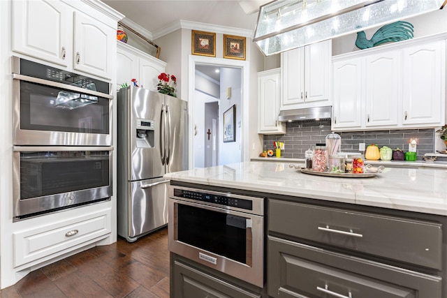 kitchen featuring white cabinetry, ornamental molding, stainless steel appliances, and light stone countertops