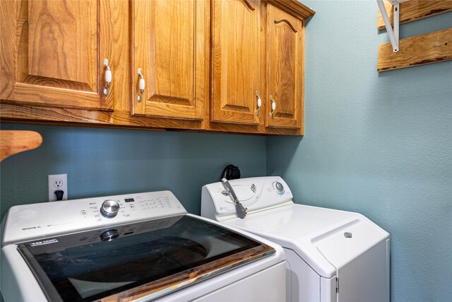 laundry area featuring washer and clothes dryer and cabinets