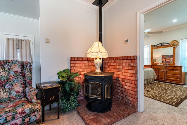 carpeted living room featuring crown molding, a wood stove, and ceiling fan