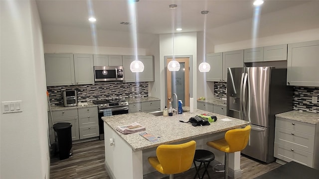 kitchen featuring light stone countertops, appliances with stainless steel finishes, sink, a kitchen breakfast bar, and a kitchen island with sink