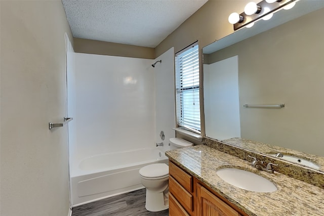 full bathroom featuring toilet, hardwood / wood-style floors, bathtub / shower combination, a textured ceiling, and vanity