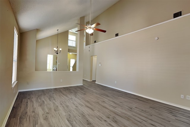 unfurnished living room with high vaulted ceiling, wood-type flooring, a wealth of natural light, and ceiling fan with notable chandelier