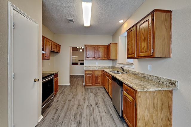 kitchen featuring light hardwood / wood-style floors, stainless steel appliances, a textured ceiling, light stone counters, and sink