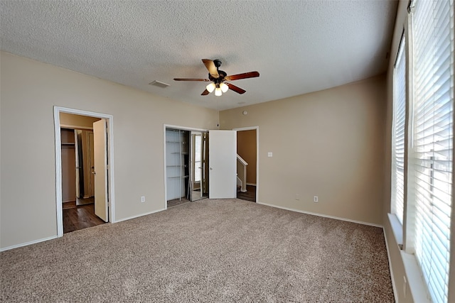 unfurnished bedroom featuring a textured ceiling, ceiling fan, and dark colored carpet