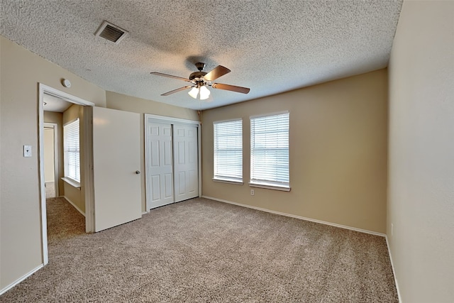 unfurnished bedroom with a textured ceiling, ceiling fan, a closet, and light colored carpet