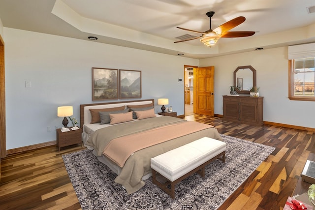 bedroom featuring a tray ceiling, dark hardwood / wood-style floors, and ceiling fan