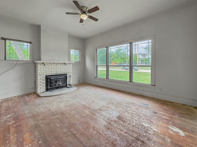 unfurnished living room with a brick fireplace, ceiling fan, baseboards, and wood-type flooring