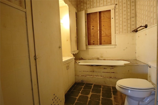 bathroom with a tub to relax in and toilet