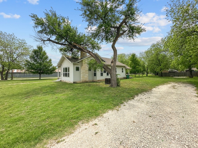 view of side of property featuring a lawn, fence, and central air condition unit