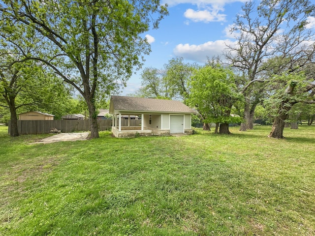 exterior space featuring fence, a shingled roof, and a lawn