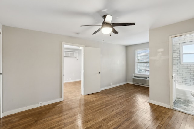 unfurnished bedroom with ceiling fan, hardwood / wood-style floors, ensuite bathroom, and a wall mounted AC