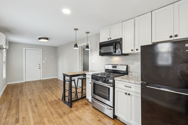 kitchen with black appliances, hanging light fixtures, light wood-type flooring, white cabinets, and light stone counters