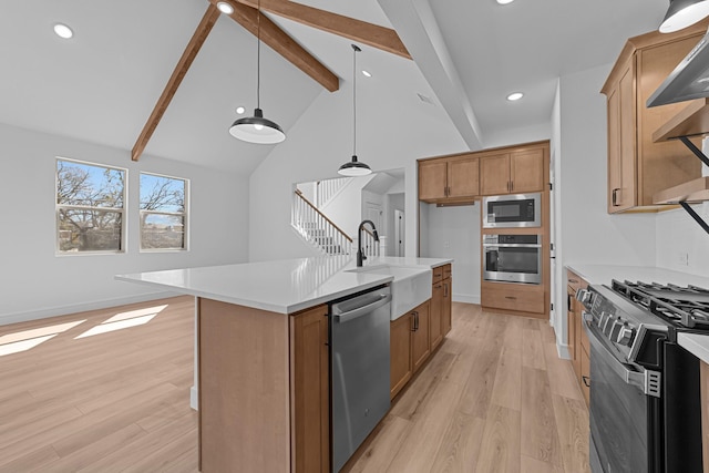 kitchen featuring light wood-type flooring, appliances with stainless steel finishes, a sink, and beamed ceiling