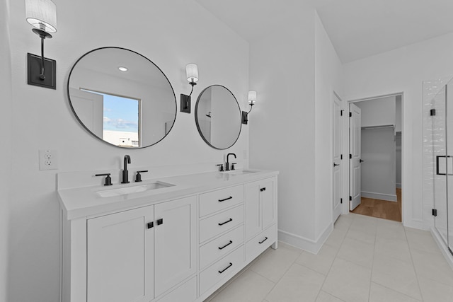 bathroom with double vanity, a shower stall, and a sink