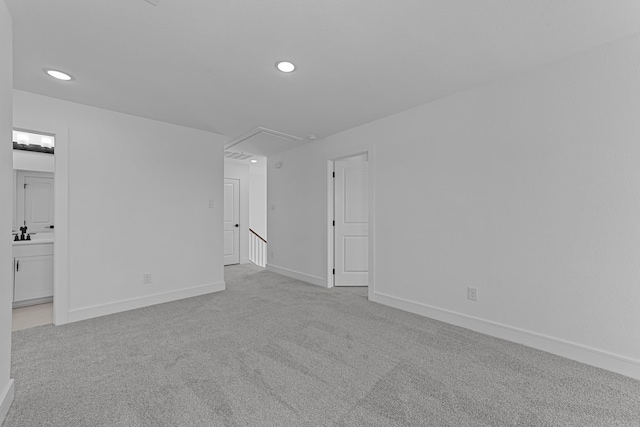 interior space with recessed lighting, attic access, light carpet, a sink, and baseboards