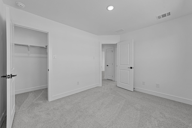 unfurnished bedroom with carpet floors, visible vents, baseboards, a closet, and a walk in closet