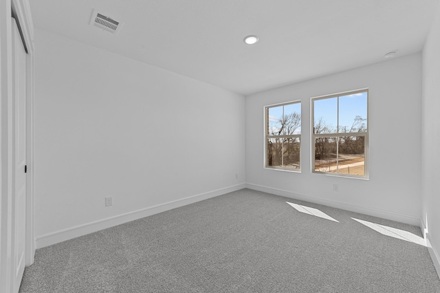 carpeted empty room featuring recessed lighting, visible vents, and baseboards