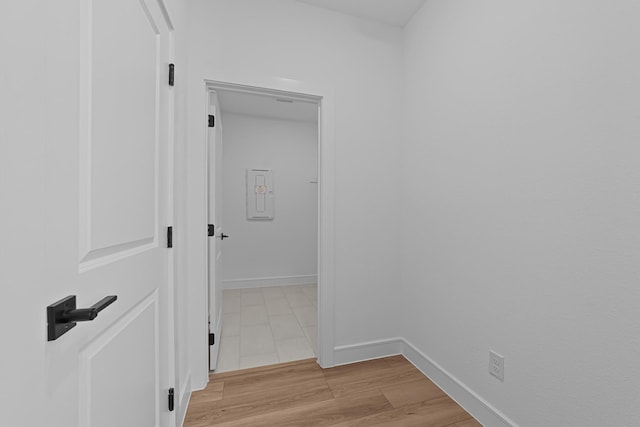 hall with baseboards and light wood-style floors