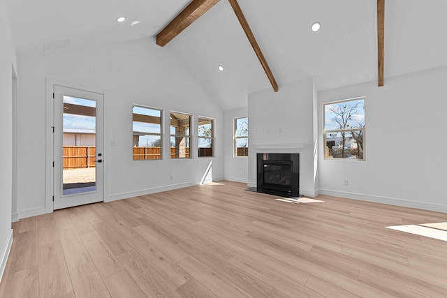 unfurnished living room with light wood-style floors, beamed ceiling, high vaulted ceiling, and a fireplace with flush hearth