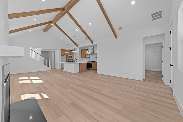 unfurnished living room with visible vents, stairs, light wood-style floors, high vaulted ceiling, and beam ceiling