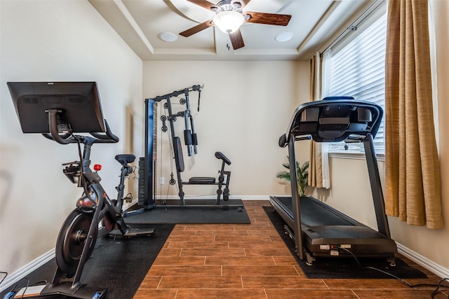 exercise room with ceiling fan and a raised ceiling