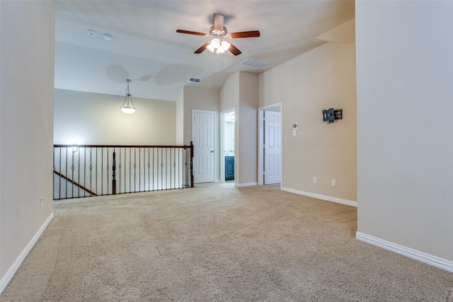 carpeted spare room with ceiling fan and vaulted ceiling