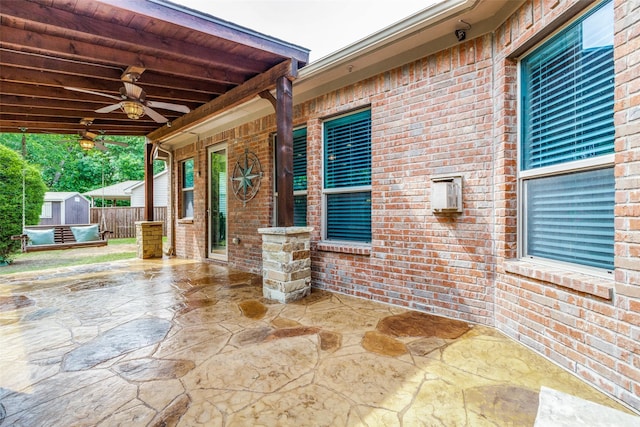 view of patio with ceiling fan and a shed