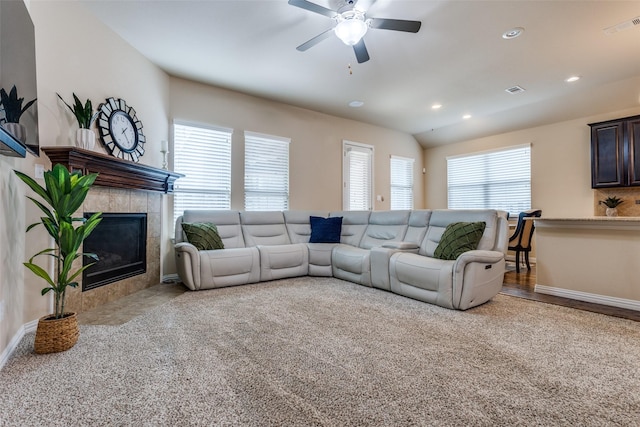 carpeted living room featuring ceiling fan, a tile fireplace, and vaulted ceiling