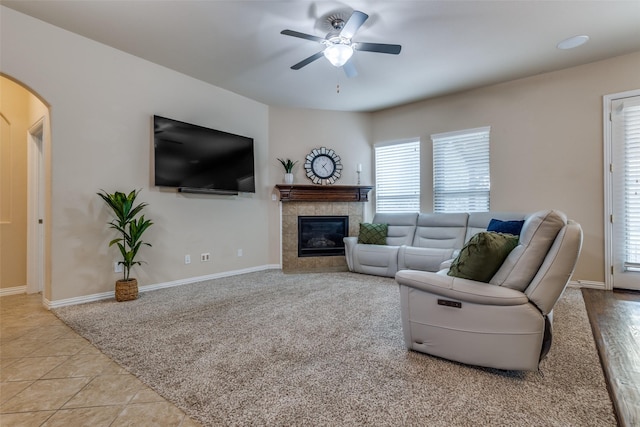 tiled living room with a tile fireplace and ceiling fan