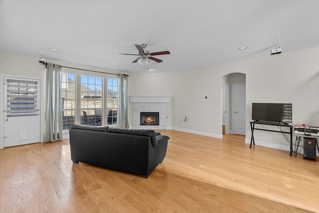 living room with a fireplace, light hardwood / wood-style floors, and ceiling fan