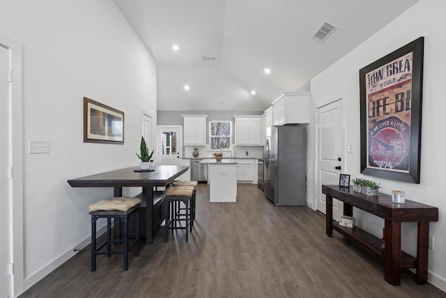 kitchen featuring white cabinetry, stainless steel appliances, a center island, and a kitchen bar