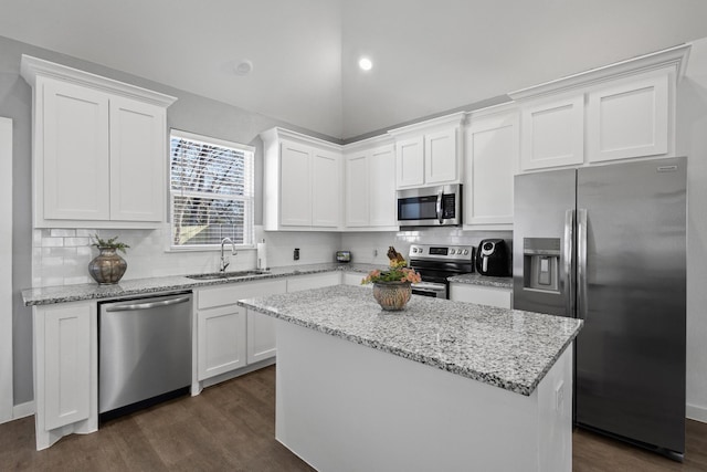 kitchen with lofted ceiling, sink, a kitchen island, stainless steel appliances, and white cabinets