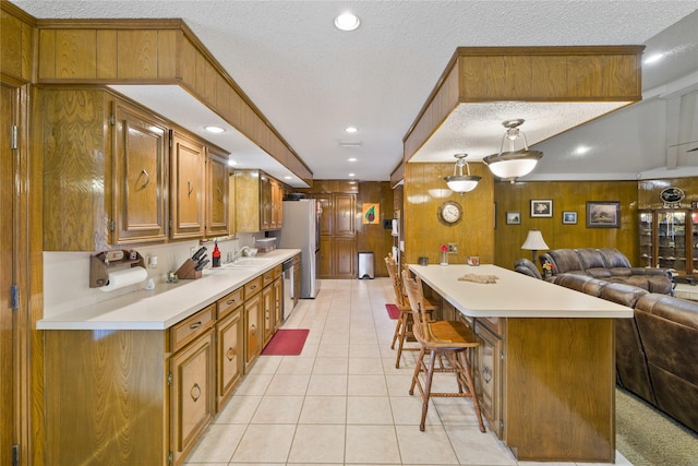 kitchen with stainless steel appliances, light countertops, open floor plan, a textured ceiling, and brown cabinets