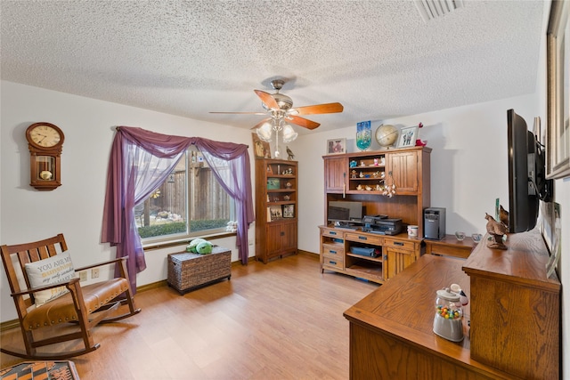 office area featuring a textured ceiling, light wood-style flooring, visible vents, and ceiling fan