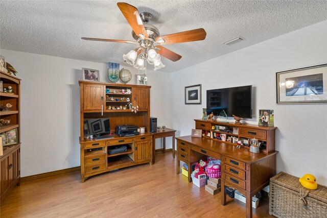 home office with visible vents, a textured ceiling, light wood-style flooring, and a ceiling fan