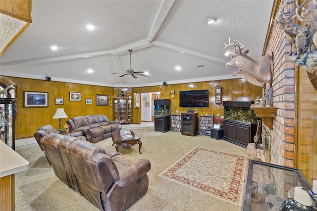 living area with vaulted ceiling with beams, wood walls, carpet flooring, a fireplace, and a textured ceiling