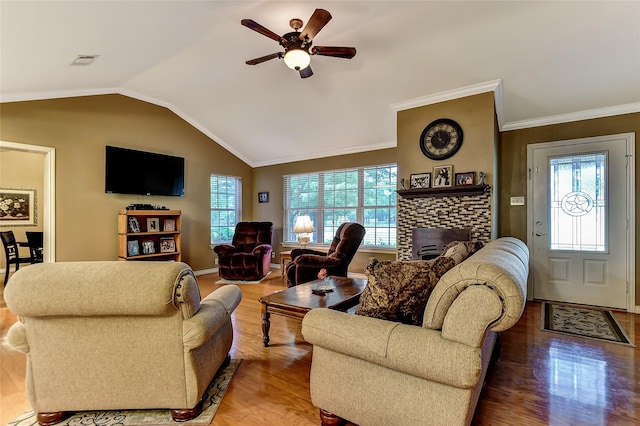 living room with ceiling fan, vaulted ceiling, a brick fireplace, hardwood / wood-style flooring, and ornamental molding