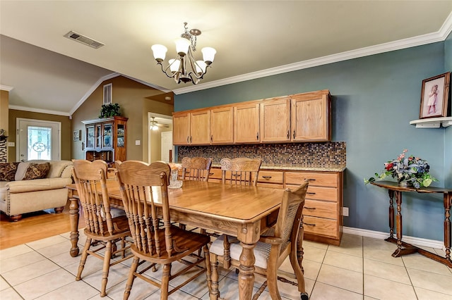 dining room featuring light tile patterned floors, crown molding, a notable chandelier, and lofted ceiling