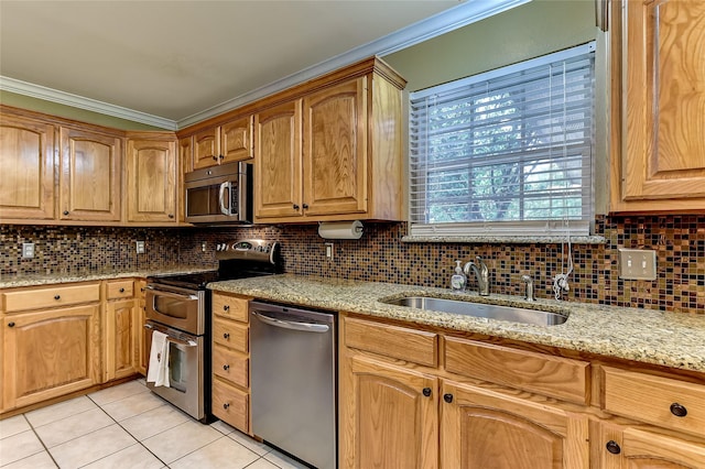 kitchen with sink, light tile patterned flooring, light stone countertops, appliances with stainless steel finishes, and ornamental molding