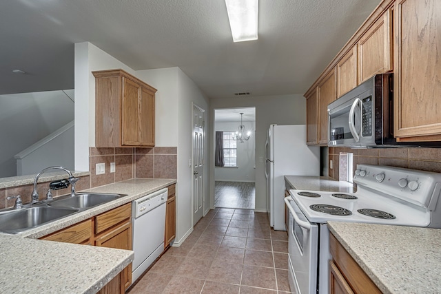 kitchen featuring white appliances, a chandelier, light tile patterned floors, decorative backsplash, and sink