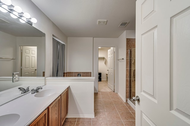 bathroom with tile patterned flooring, vanity, a textured ceiling, and walk in shower