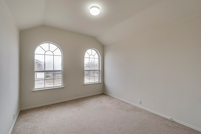 unfurnished room featuring light colored carpet and lofted ceiling