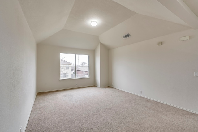 carpeted empty room with vaulted ceiling