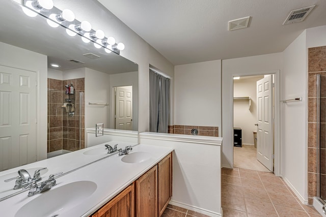 bathroom featuring a tile shower, tile patterned flooring, and vanity