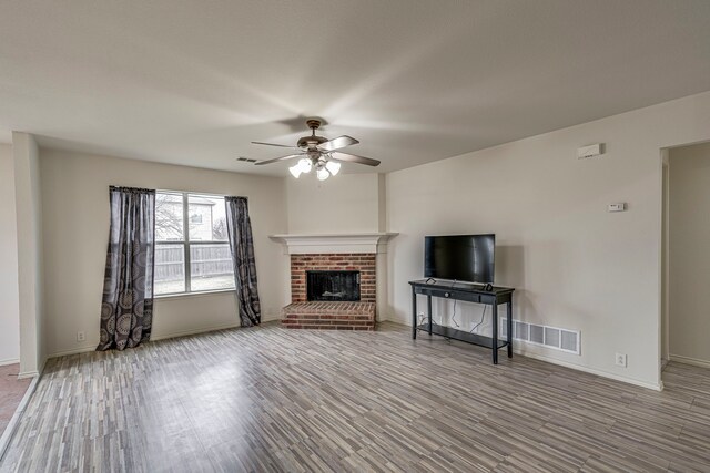 unfurnished living room with ceiling fan, light hardwood / wood-style flooring, and a brick fireplace