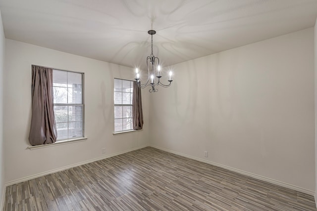 unfurnished room with a notable chandelier and hardwood / wood-style flooring