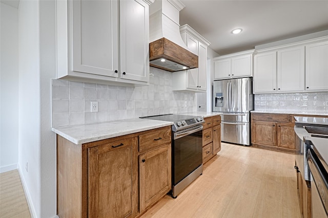 kitchen with white cabinets, light hardwood / wood-style flooring, stainless steel appliances, and custom range hood